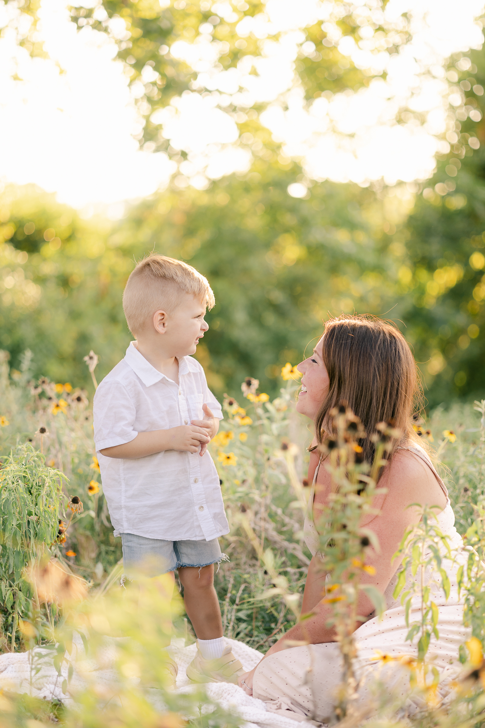 young boy and mother sitting in golden hour wildflower field