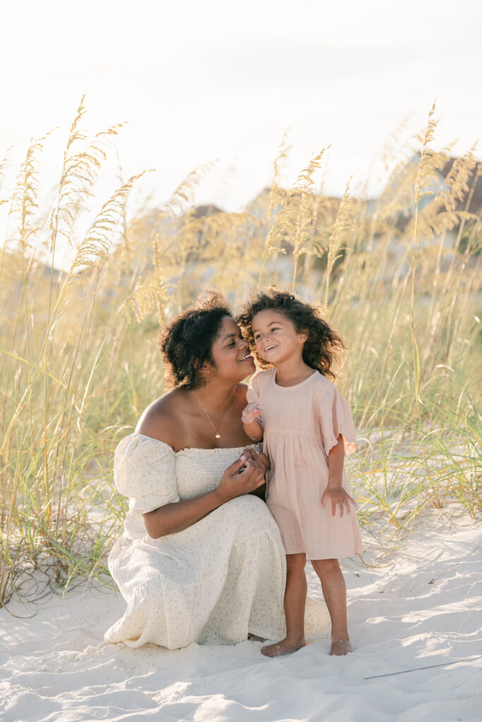 black woman kneeling and whispering to her young daughter on the beach