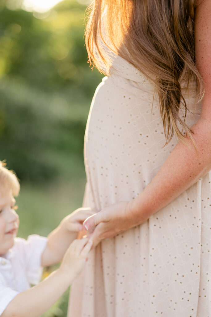 pregnant woman in tan eyelet maxi dress with young boy holding her hand