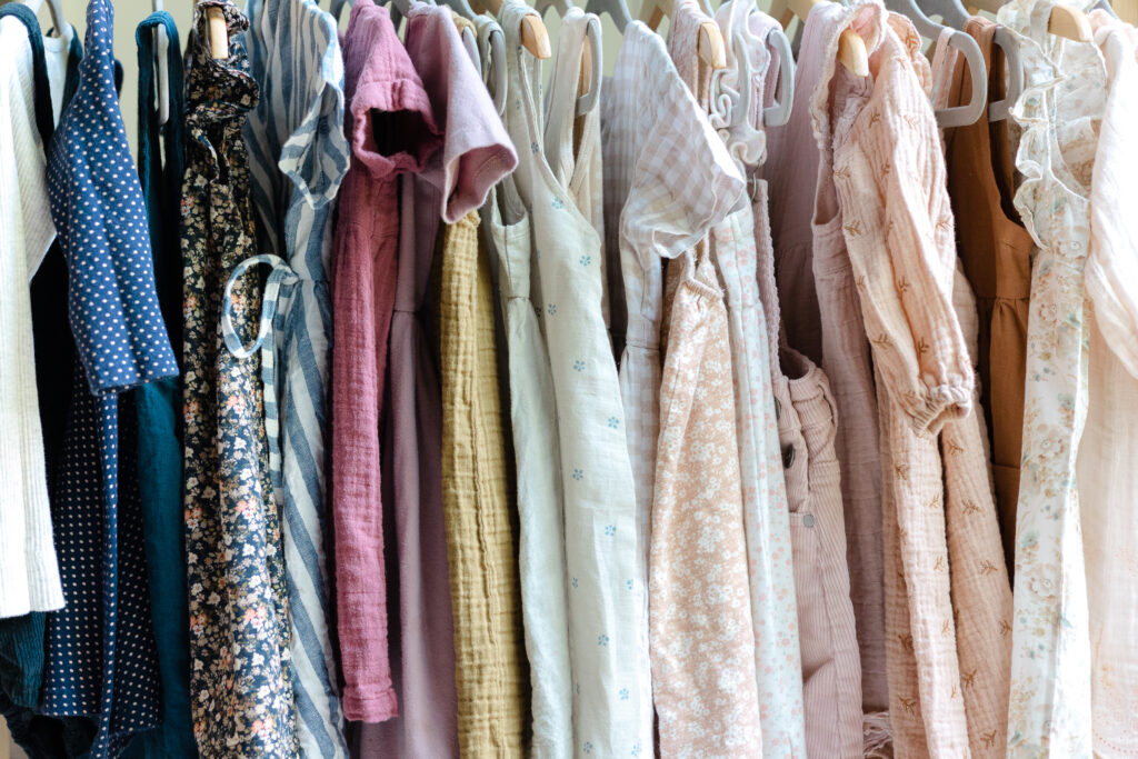 clothing rack filled with children's clothing in a neutral, soft toned color palette 